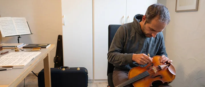 Paul arbeitet mit einem Werkzeug an einer Geige in seinem Arbeitszimmer